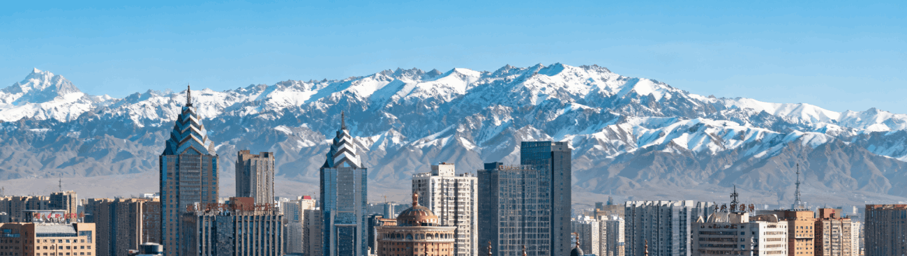 City buildings beneath snow-covered mountains in Xinjiang